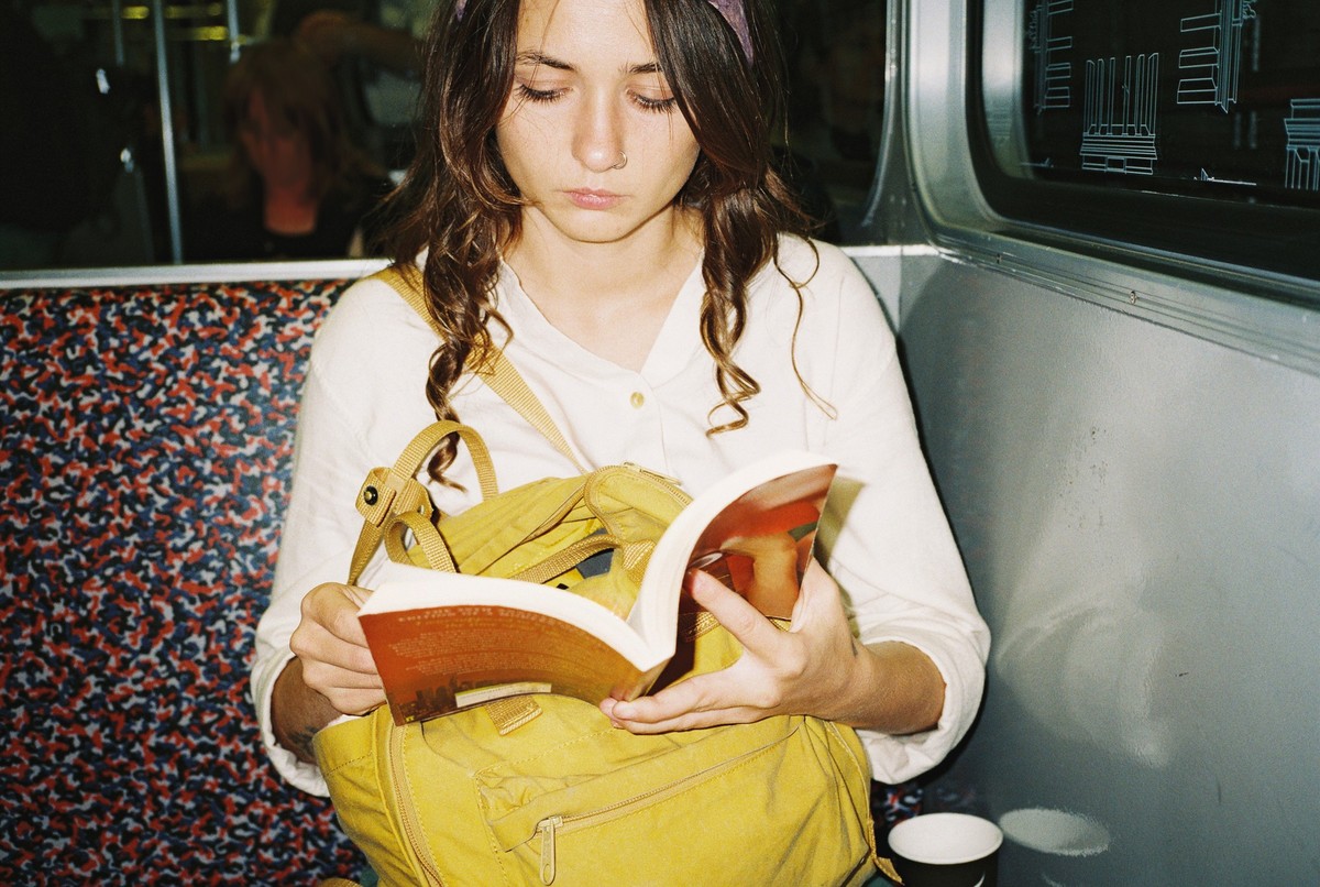 Young woman reading book in subway, shot with flash on film