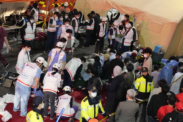 Rescue workers treat injured people on the street near the scene in Seoul, South Korea, Sunday, Oct. 30, 2022. South Korean officials say at least 120 people were killed and 100 more were injured as t ...
