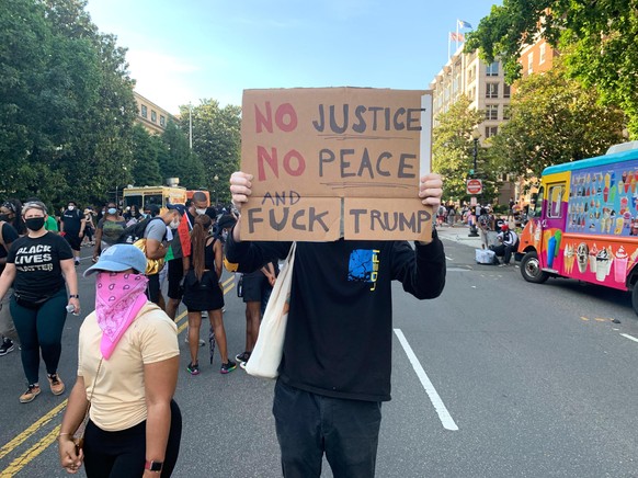 06.06.2020, USA, Washington: Ein Demonstrant nimmt mit einem Schild auf dem &quot;No justice - No peace - and fuck Trump&quot; steht, an einem Protest gegen Raissmus teil. Washington hat sich zu einem ...