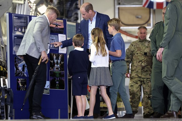 Britain&#039;s Prince William, center, stands with Prince George of Wales, Princess Charlotte of Wales and Prince Louis of Wales as they read information on a board inside a C17 plane during their vis ...