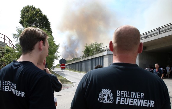 Einsatzkräfte der Berliner Feuerwehr vor einer Rauchsäule.