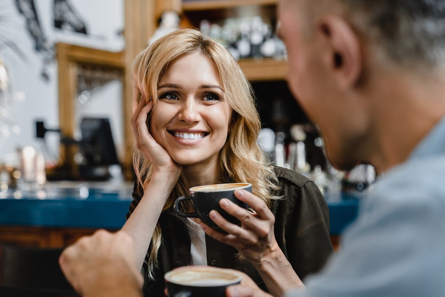 Interested excited falling in love mature woman listening to her husband man boyfriend while drinking coffee in restaurant cafe on a date