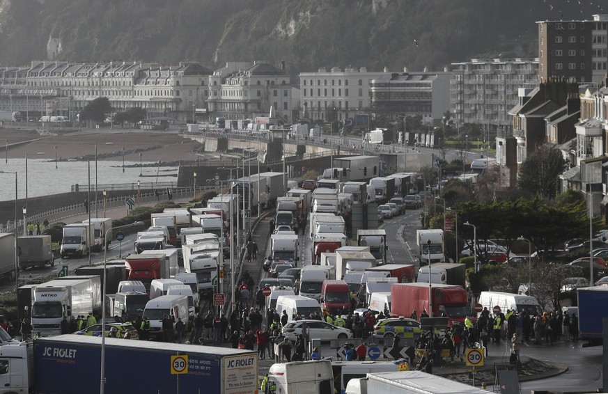 Vehicles wait at the entrance to the Port of Dover, that is blocked by police, as they queue to be allowed to leave, in Dover, England, Wednesday, Dec. 23, 2020. Freight from Britain and passengers wi ...