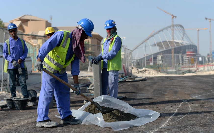 Gastarbeiter aus Indien und Bangladesch bringen am 11.01.2017 an einer Straße vor dem Khalifa-Stadion in Doha, Katar, einen Bordstein an. Foto: Andreas Gebert/dpa