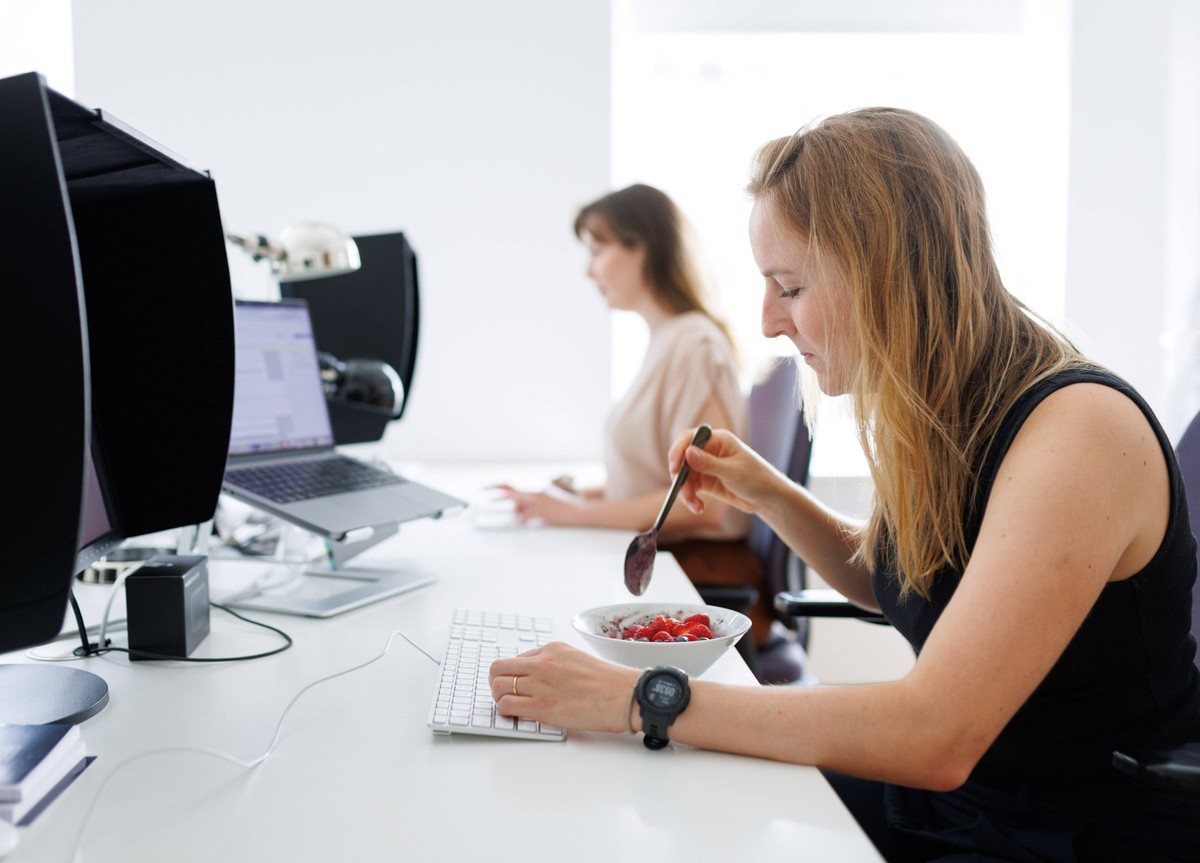 Thema Essen am Arbeitsplatz: Eine Frau isst ein Muesli mit Fruechten im Buero. Berlin, 25.07.2024. Berlin Deutschland *** Topic Eating at work A woman eats a muesli with fruits in the office Berlin, 2 ...
