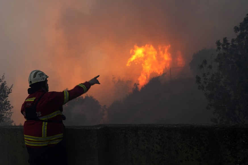 25.07.2023, Portugal, Alcabideche: Ein Feuerwehrmann zeigt auf den Waldbrand, der in Alcabideche, außerhalb von Lissabon, wütet. Hunderte von Feuerwehrleuten und mehr als ein Dutzend Flugzeuge bekämpf ...