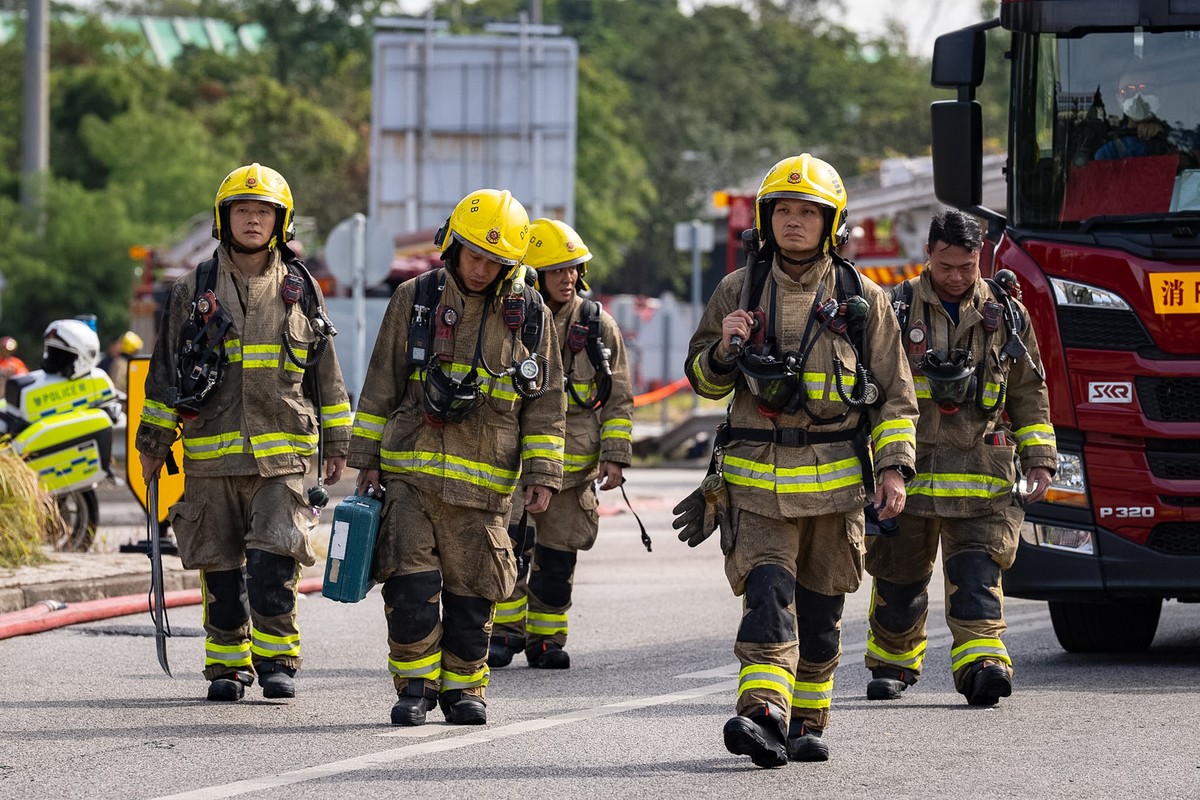 28.11.2025, Hongkong: Feuerwehrleute gehen in der Nähe des tödlichen Brandes im Wang Fuk Court, einer Wohnsiedlung im Stadtteil Tai Po. Foto: Chan Long Hei/AP/dpa +++ dpa-Bildfunk +++
