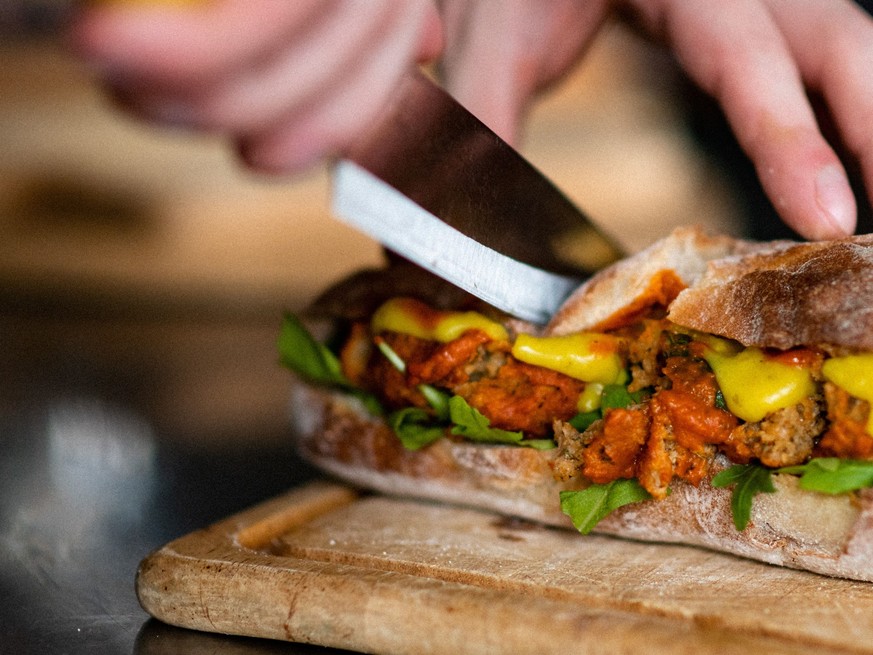 RECORD DATE NOT STATED A closeup shot of hands cutting a vegan sandwich with a knife *** einer closeupe erschossen des H