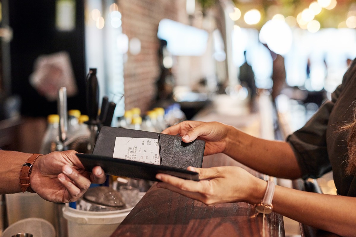 Hands with bill, food service and people in restaurant, customer with receipt and payment with cashier or waiter. Fine dining, dinner and check at cafe, catering and hospitality with finance