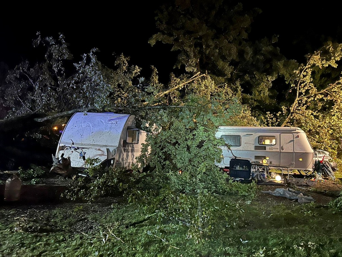 24.08.2023, Bayern, Lindau: Bäume liegen nach einem Unwetter auf Campingwagen auf einem Campingplatz. Bei einem schweren Unwetter sind am Donnerstag auf einem Campingplatz in Lindau am Bodensee mehrer ...