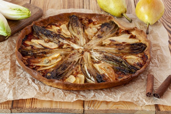 sweety salty endives, pear and gorgonzola tart on a wooden background, side view