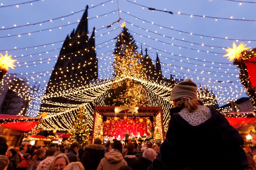 Lichter und Weihnachtsbuden auf einem Weihnachtsmarkt am Dom in Köln. Deutschlands beliebtester Weihnachtsmarkt befindet sich direkt vor der prachtvollen Kulisse des Kölner Doms. Vier Millionen Mensch ...