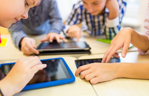 education, elementary school, learning, technology and people concept - close up of school kids with tablet pc computers having fun and playing on break in classroom