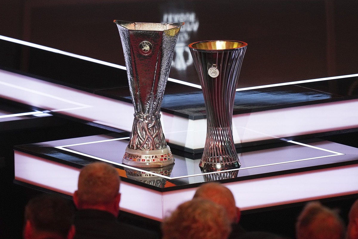 The Conference League trophy and the Europa League trophy are displayed during the soccer league phase draw in Monaco, Friday, Aug. 29, 2025. (AP Photo/Laurent Cipriani)