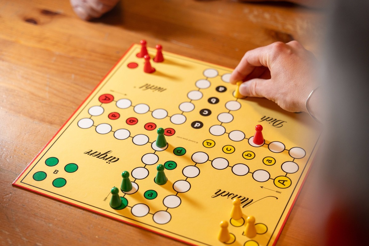 Kammlach, Bavaria, Germany - 1 July 2023: A family plays the board game Mensch ärgere dich nicht. Game board with dice and game pieces *** Eine Familie spielt das Brettspiel Mensch ärgere dich nicht.  ...