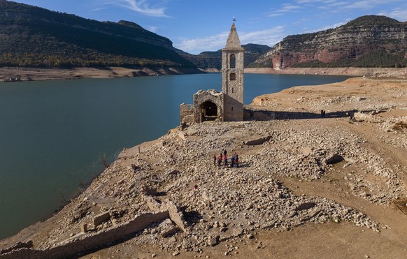 ARCHIV - 23.11.2022, Spanien, Vilanova de Sau: Eine Kirche und die Überreste eines alten Dorfes, die normalerweise vom Wasser bedeckt werden, sind im Inneren des Stausees von Sau zu sehen. Der trocken ...