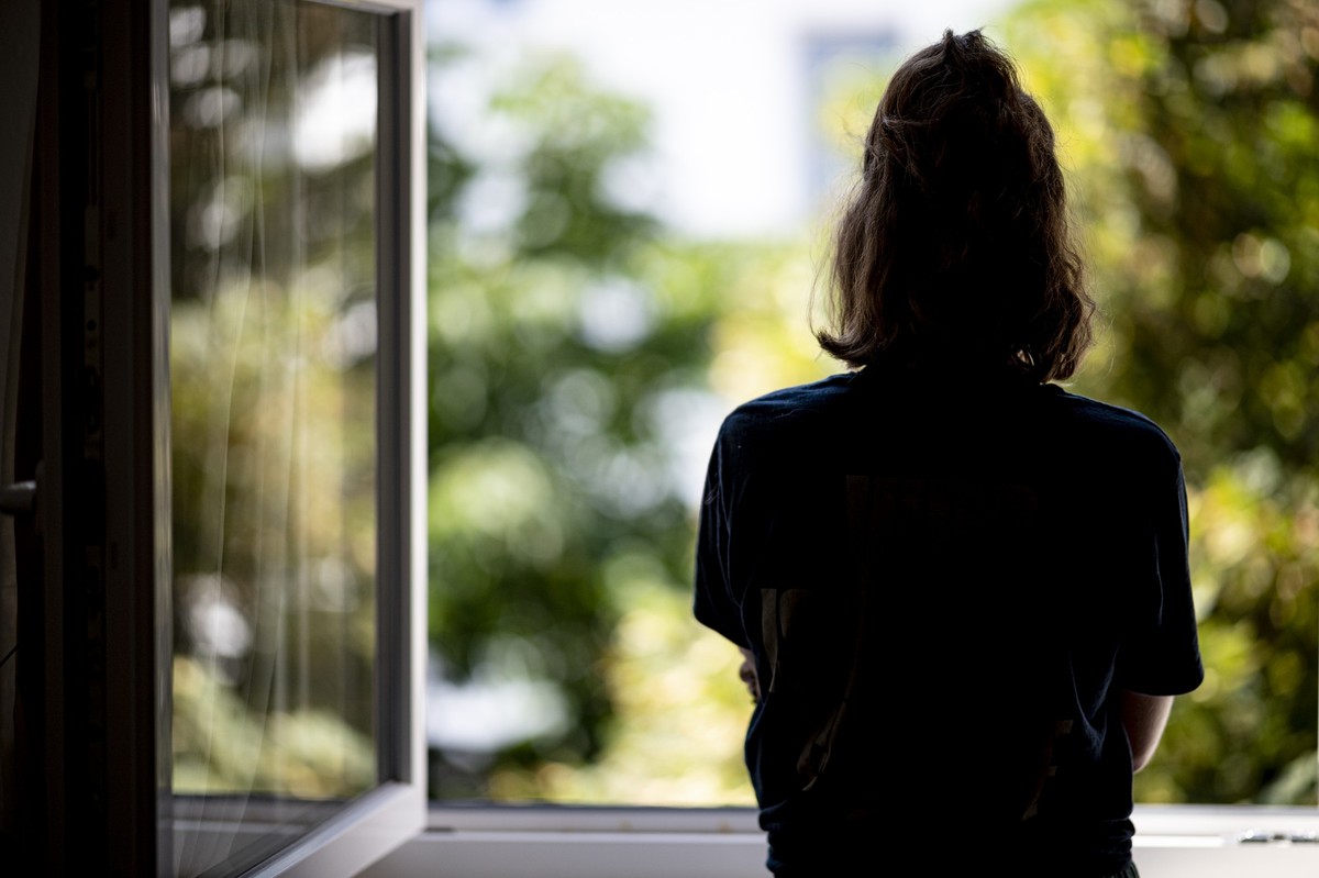 ARCHIV - 13.07.2021, Berlin: ILLUSTRATION - Eine Frau steht in ihrer Wohnung an einem Fenster. (zu dpa:
