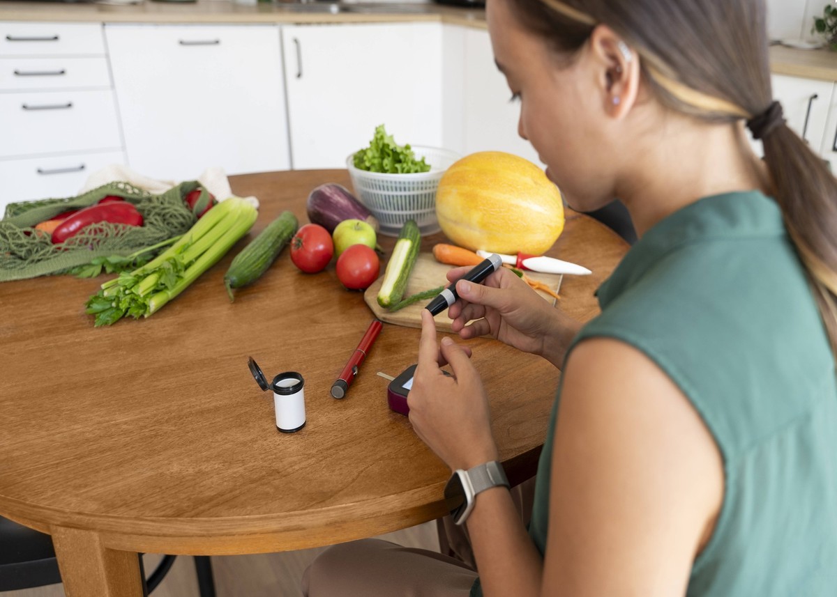 Young woman checking sugar level using glucometer sitting at kitchen table model released, Symbolfoto property released, VRAF00876