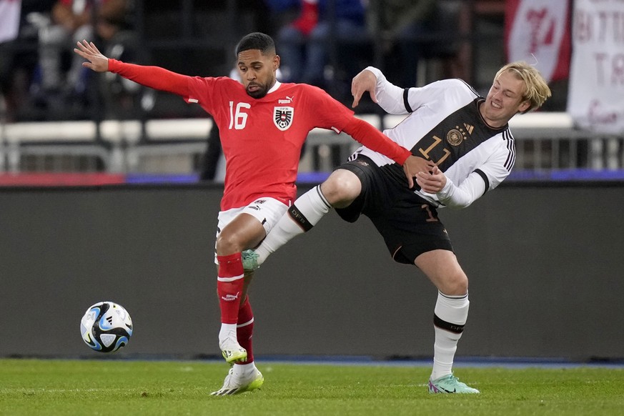 21.11.2023, Österreich, Wien: Fußball: Länderspiele, Österreich - Deutschland, Ernst-Happel-Stadion. Deutschlands Julian Brandt (r) und Österreichs Phillipp Mwene kämpfen um den Ball. Foto: Matthias S ...