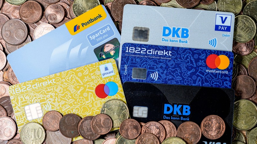 Diverse Kreditkarten, EC-Karten und Sparkassenkarten liegen auf einem Haufen Kleingeld, Kundenkarten der Banken 1822 direkt, Frankfurter Sparkasse, Postbank, VISA, Mastercard und DKB, Kreditkarte, EC- ...