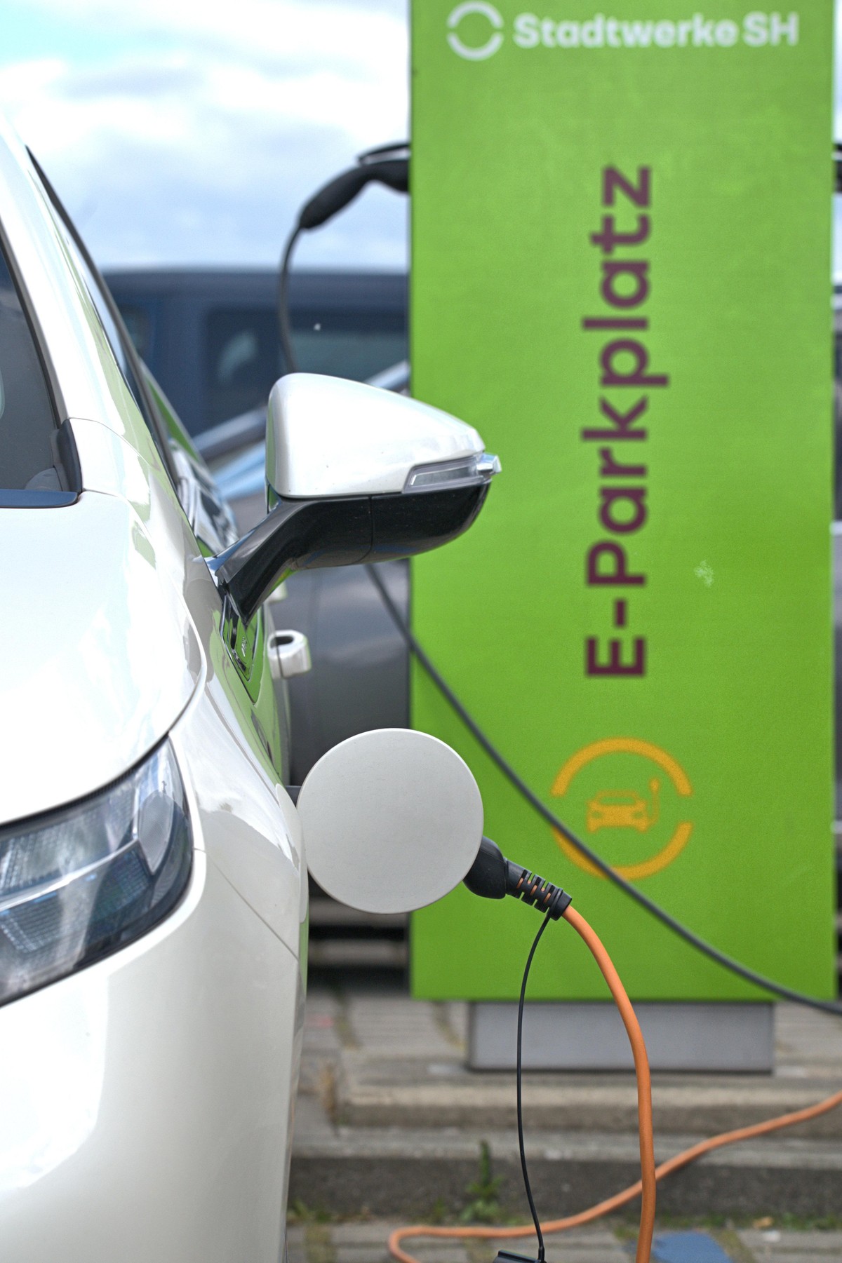 Schleswig, ein weißer, elektrischer Opel Ampera steht mit einem orangenen Ladekabel zum Aufladen auf einem E-Parkplatz der Stadtwerke SH am Schleswiger Stadthafen. Der Ampera hat den Anschluss für den ...