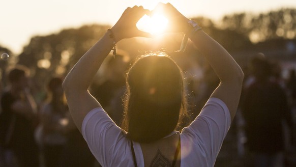 19/ Festivalbesucherin Rebecca aus Berlin zeigt mit ihren Haenden ein Herz vor der untergehenden Sonne beim Lollapalooza Festival auf der Trabrennbahn Hoppegarten am 10. September 2017. Sonne einfange ...