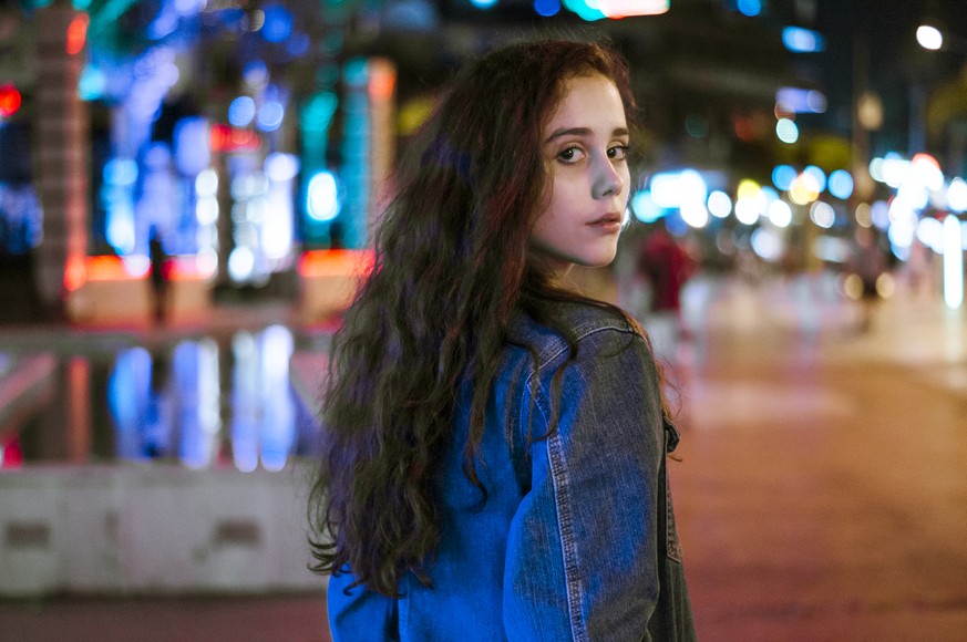 Portrait of pretty serious girl walking in the night neon lights city