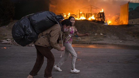 dpatopbilder - 09.09.2020, Griechenland, Moria: Migranten fliehen vor neu ausgebrochenen Feuern mit ihren Habseligkeiten aus dem Flüchtlingslager Moria, nachdem zuvor bereits mehrere Brände das Lager  ...