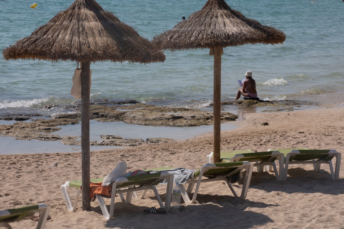 30.06.2025, Spanien, Llucmajor: Eine Frau liest ein Buch am Strand von Arenal auf Mallorca. Foto: Clara Margais/dpa +++ dpa-Bildfunk +++