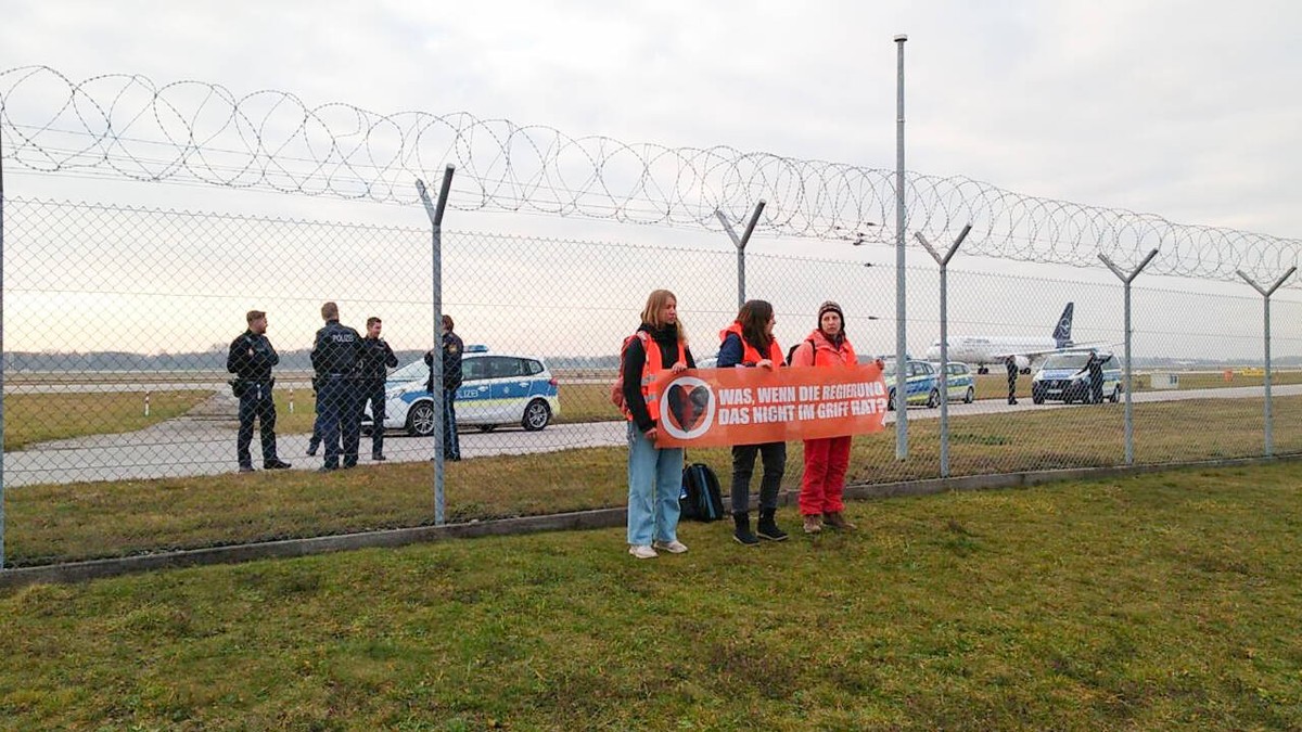 Letzte Generation demonstriert am Flughafen M�nchen Aktivist*innen der Letzten Generation demonstrierten am 8.12.2022 vor dem Stcheldrahtzaun des M�nchner Flughafens f�r die Wiedereinf�hrung des Neun- ...