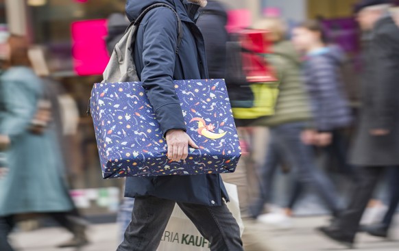 ARCHIV - 23.12.2019, Hessen, Frankfurt/Main: Ein Mann eilt mit einem verpackten Geschenk zwischen den anderen Passanten die Einkaufsmeile Zeil entlang. (zu dpa: «Mehrheit der Tarifbeschäftigten erhält ...