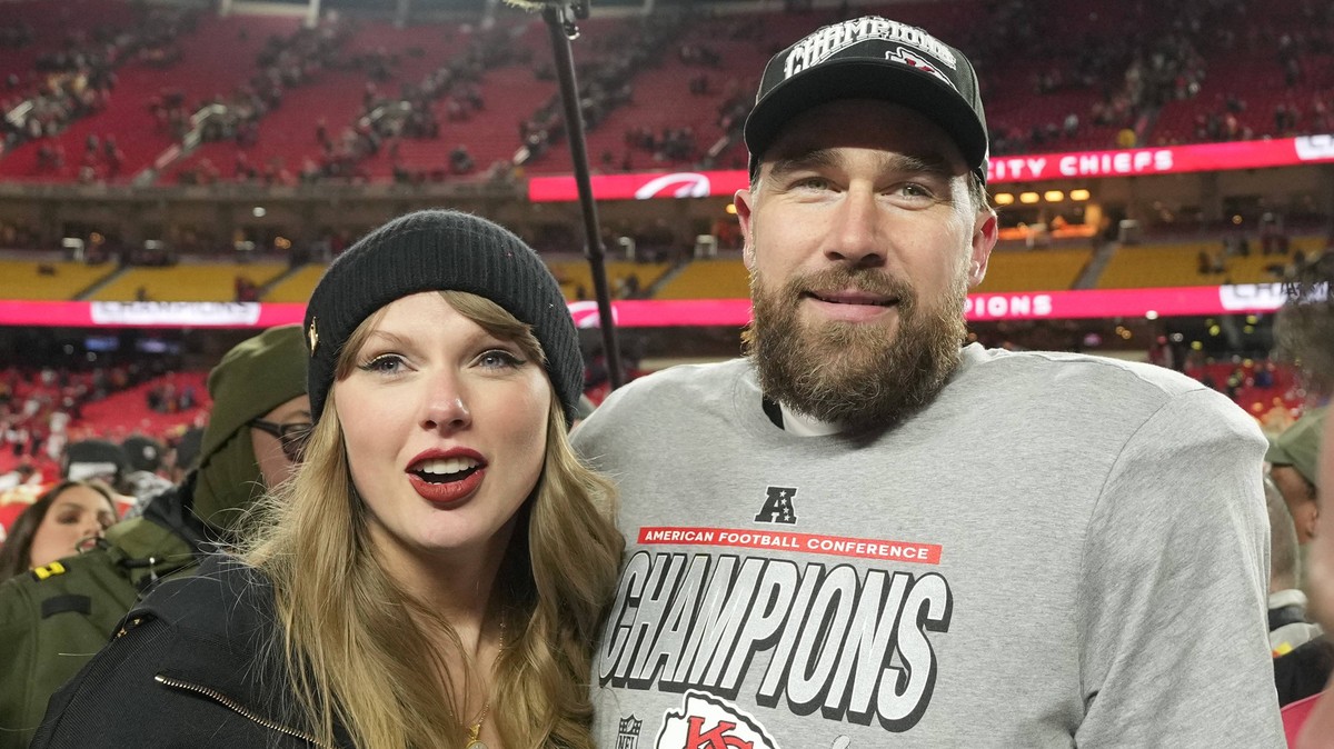 Kansas City Chiefs tight end Travis Kelce and his girlfriend entertainer Taylor Swift stand on the field after the Chiefs defeated the Buffalo Bills 32-29 in the AFC Championship Game at Arrowhead Sta ...