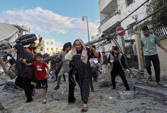 Palestinian families rush out of their homes after Israeli airstrikes in their neighborhood in Gaza City, central Gaza Strip, Tuesday, Oct. 17, 2023. (AP Photo/Abed Khaled)