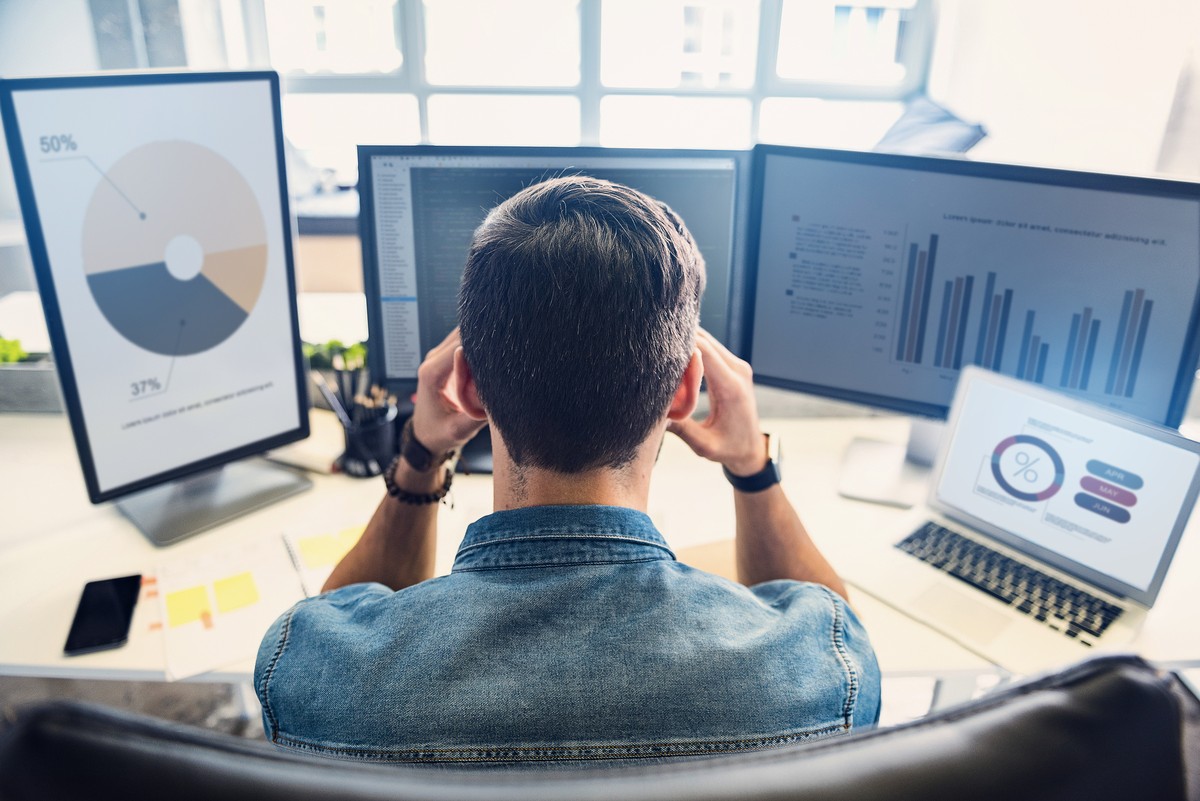 I have headache. Employee demonstrating weariness while having job on computer in apartment. He is looking at graphics on monitor with concentration