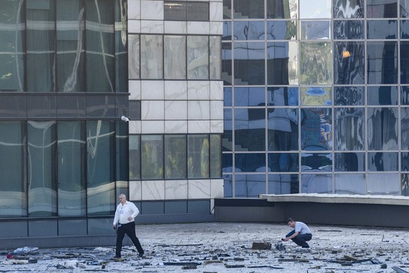 01.08.2023, Russland, Moskau: Ermittler untersuchen einen Bereich neben einem beschädigten Gebäude im Geschäftsviertel «Moscow City» nach einem gemeldeten Drohnenangriff. Die russische Hauptstadt ist  ...