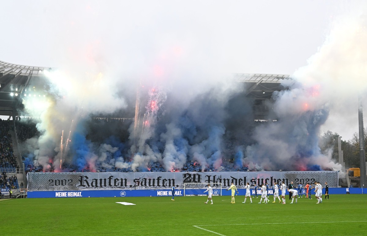 ARCHIV - 12.11.2022, Baden-Württemberg, Karlsruhe: Fußball, 2. Bundesliga, Karlsruher SC - FC St. Pauli, 17. Spieltag, BBBank Wildpark: Karlsruher Fans entzünden vor Spielbeginn Rauchbomben wodurch da ...