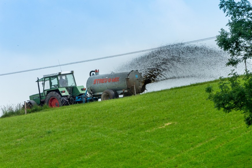 ARCHIV - 08.06.2021, Bayern, Leiten: Ein Traktor zieht eine Landwirtschaftsmaschine, mit der Gülle auf ein gemähtes Feld verteilt wird. (zu dpa: «Neue Düngeregeln in NRW: Ein Drittel der Ackerflächen  ...