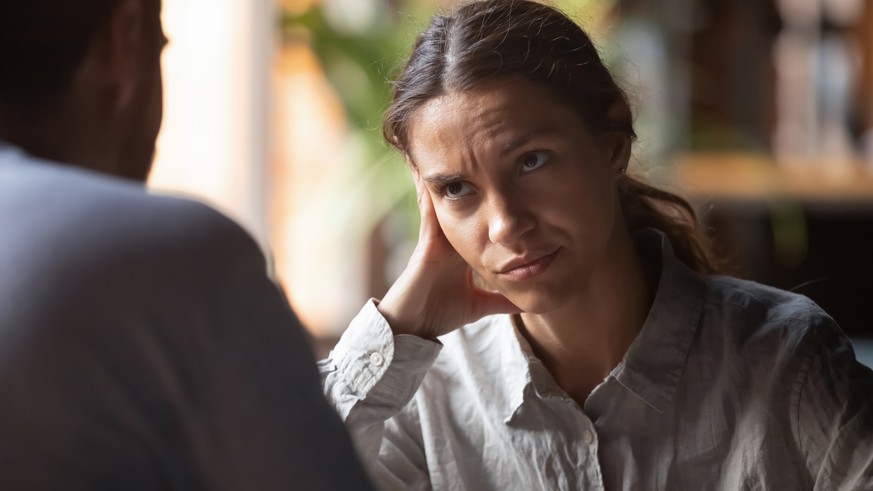 Focus on mixed race irritated young female sitting in cafeteria on speed dating with boring male rear view. Unsuccessful unlucky romantic date failure, bad first impression and poor companion concept