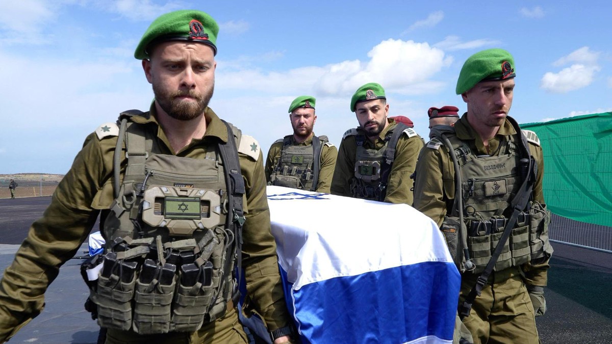 HANDOUT - 20.02.2025, Israel, -: IDF-Offiziere der israelischen Armee tragen im Gazastreifen einen der vier Särge, bedeckt mit der israelischen Flagge, die sie vom Internationalen Roten Kreuz erhalten ...