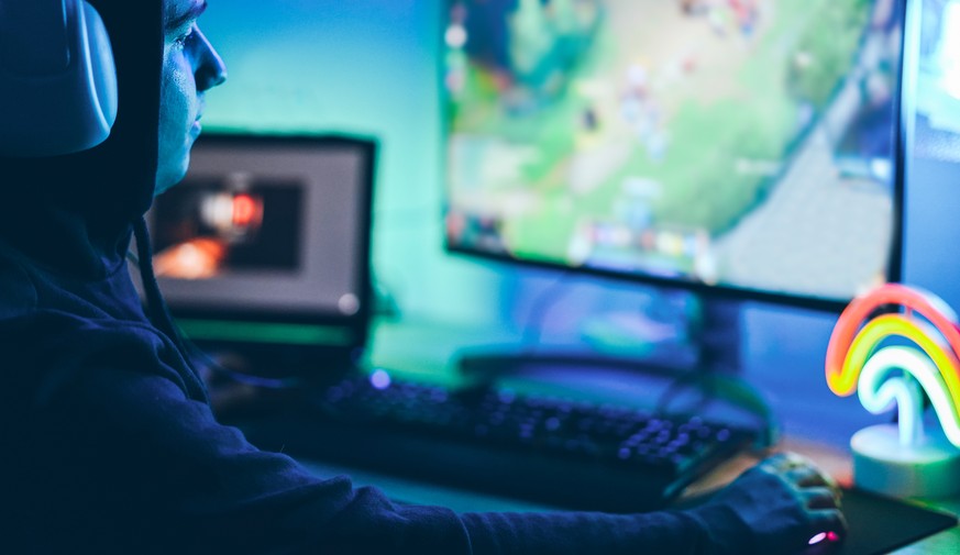 Young streamer gamer playing at strategy game in broadcast browser - Male guy having fun gaming and streaming online - New technology game trends and entertainment concept - Soft focus on his eye