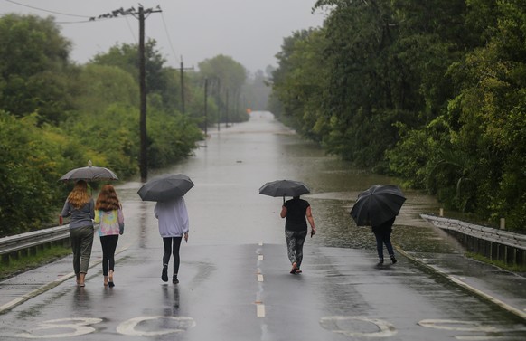 SYDNEY, AUSTRALIA - MARCH 22: People with umbrellas walk towards a flooded road in Richmond, north west of Sydney, Monday, March 22, 2021. Thousands of residents are fleeing their homes, schools are s ...