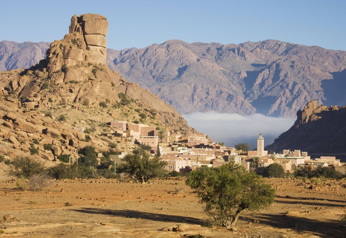 Morocco - The village of Aguard Oudad at the foot of the famous rock formation Chapeau de Napolon Napolen s hat. In the background the Djebel El Kest and the Ameln valley with early morning mist. Amel ...
