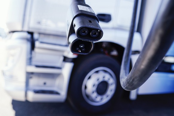 ARCHIV - 25.07.2022, Rheinland-Pfalz, Wörth am Rhein: Ein Ladestecker hängt im Mercedes-Benz Trucks KundenCenter vor einem Lastwagen. Der Tankstellenbetreiber Aral will mit einem Korridor von E-Ladesä ...