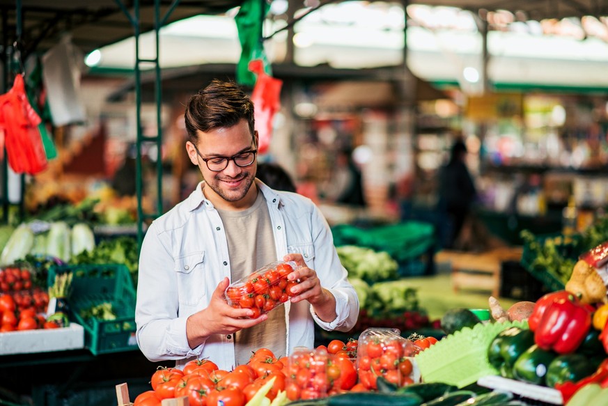 Young man buying fresh groceries at farmer&#039;s market.