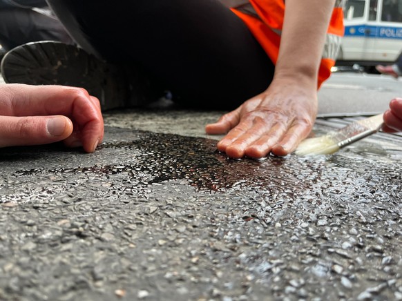 Die Protestierenden kleben sich mit Sekundenkleber auf der Straße fest.