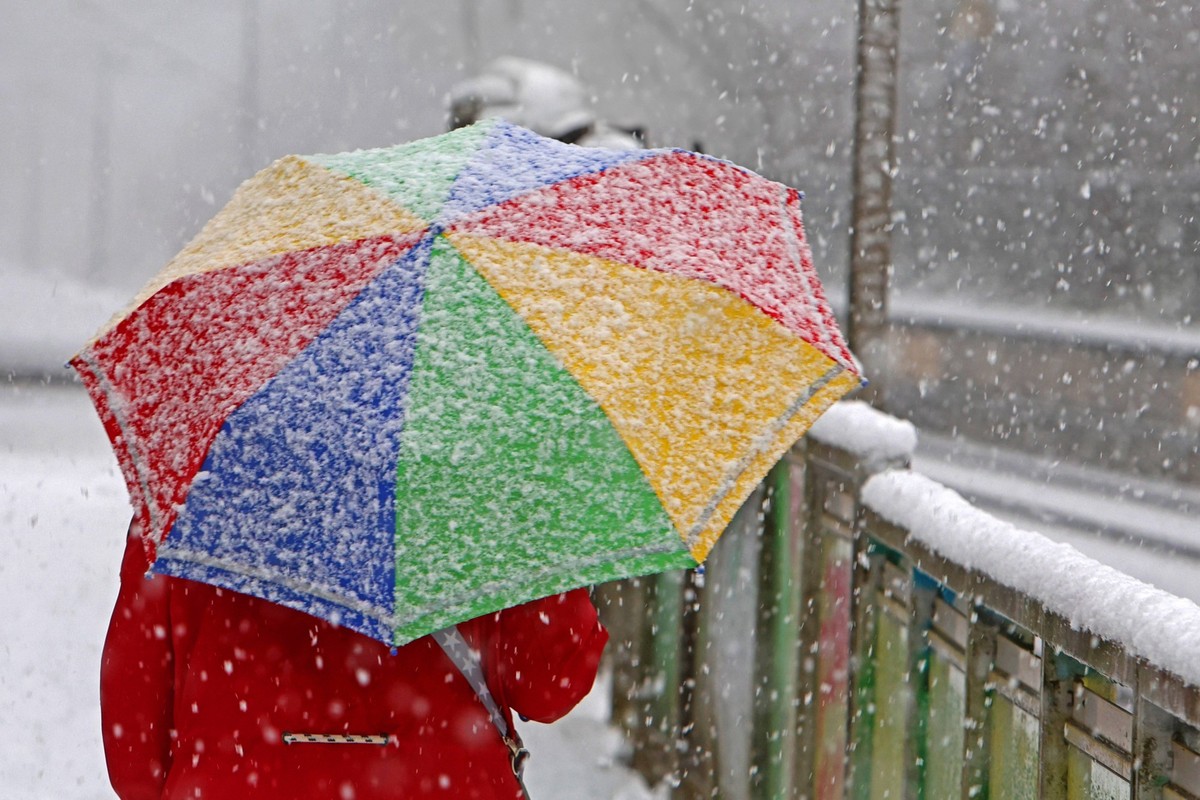 Schutz bei Schneefällen Eine Frau läuft mit einem Schirm gegen den Schnee geschützt durch die Straßen Essen Nordrhein-Westfalen Deutschland *** Protection during snowfall A woman walks through the str ...