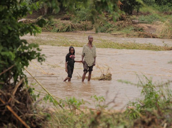 (190317) -- CHIMANIMANI (ZIMBABWE), March 17, 2019 -- People walk through a flooded river in Chimanimani, Manicaland Province, Zimbabwe, March 17, 2019. At least 31 people have been confirmed dead whi ...