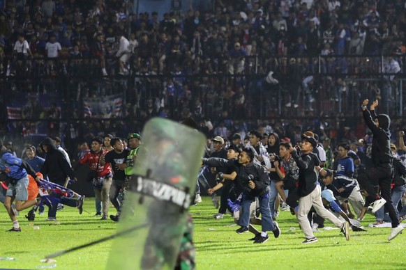 dpatopbilder - 01.10.2022, Indonesien, Malang: Fußballfans stürmen das Spielfeld während Zusammenstößen zwischen Fans im Kanjuruhan-Stadion nach dem Erstliga-Spiel zwischen Arema FC und Persebaya FC.  ...