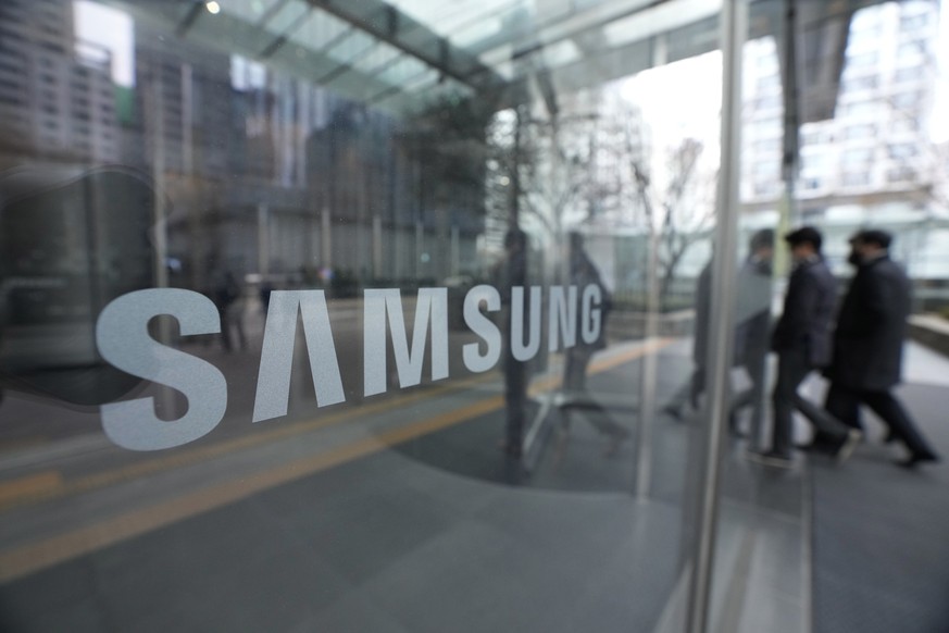 31.01.2023, Südkorea, Seoul: Mitarbeiter gehen an einem Logo der Samsung Electronics Co. an ihrem Firmengebäude vorbei. (zu dpa &quot;Samsung mit deutlich niedrigerem Betriebsgewinn&quot;) Foto: Ahn Y ...