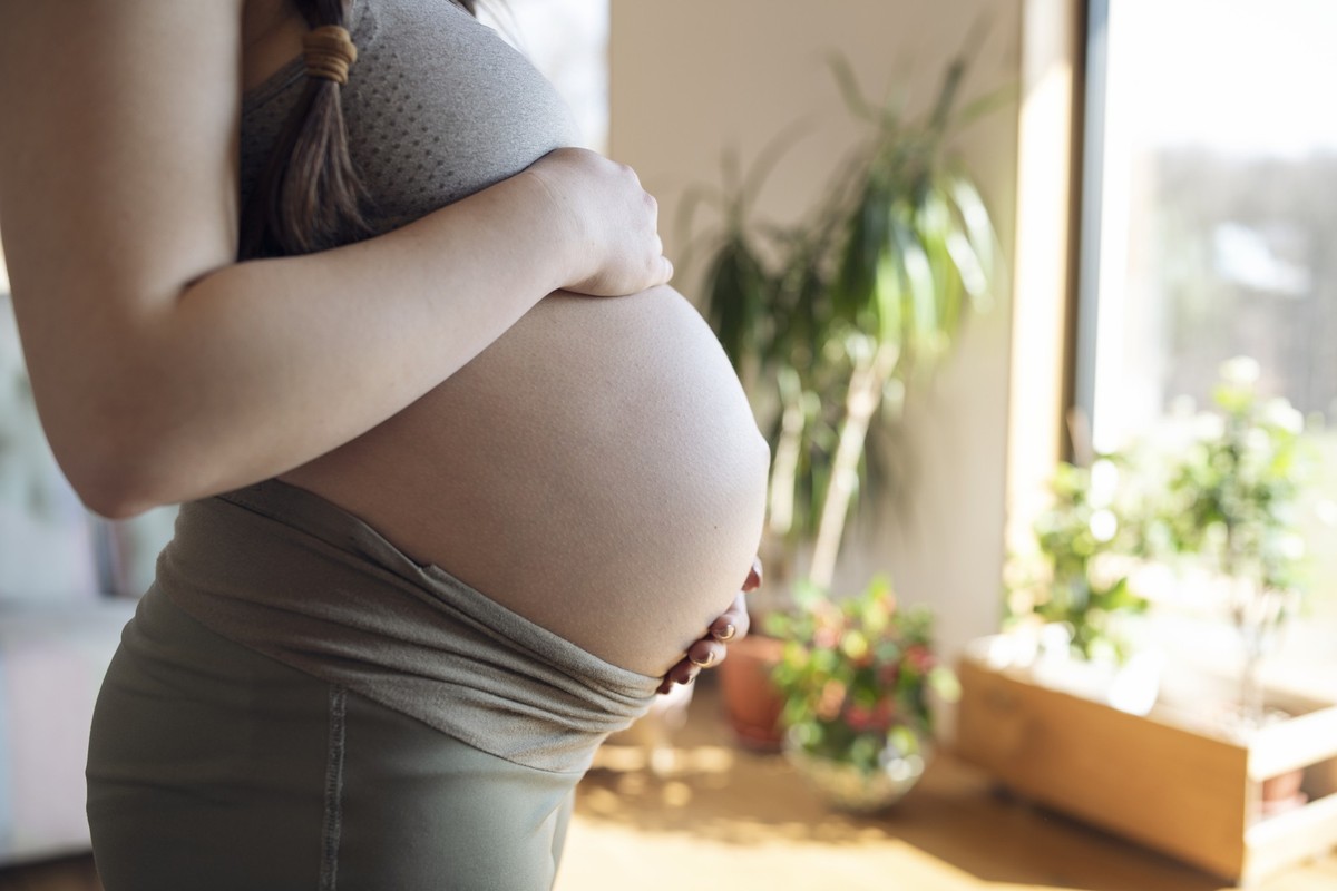 Side shot of unrecognisable pregnant woman holding belly.